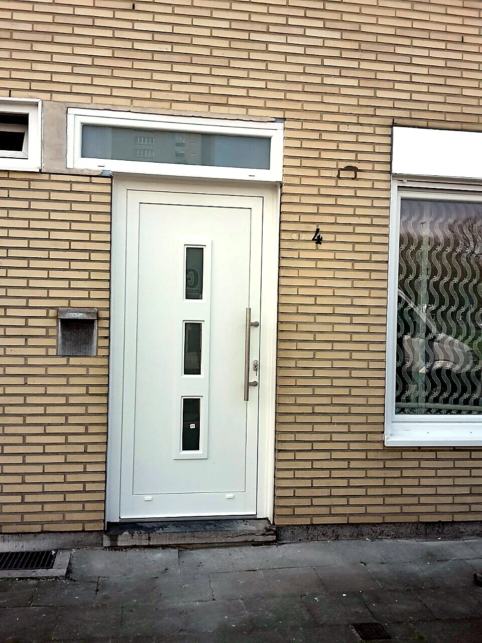 Witte inkomdeur met verticale glaspartijen